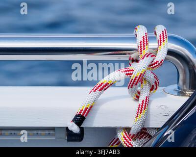 Corda rossa e bianca legata a un nodo attorno alla ringhiera di una boa Foto Stock