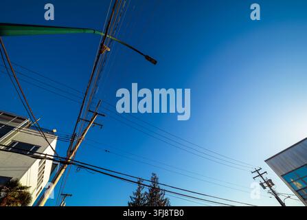 Vista ad angolazione bassa di pali della luce, lampioni e linee elettriche contro il cielo blu chiaro come spazio negativo a Vancouver, British Columbia. Foto Stock