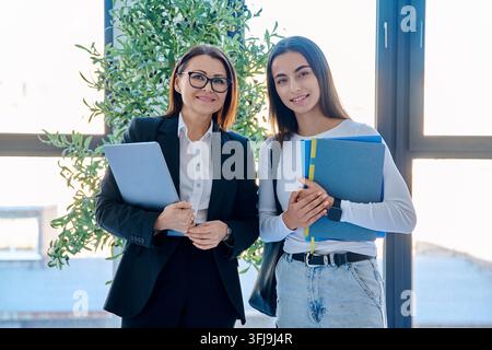 Insegnante e studentessa sorridenti in piedi insieme in un corridoio universitario Foto Stock