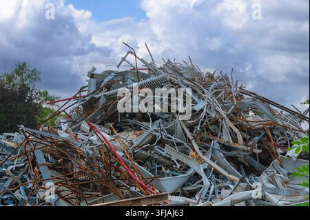 Grande pila di rottami metallici contorti e scarti di acciaio abbandonati in un centro di riciclaggio. Foto Stock