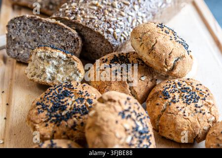 Pane artigianale fatto in casa e panini con semi su una tavola di legno Foto Stock