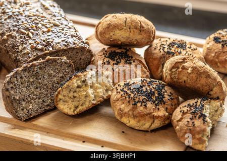 Pane artigianale fatto in casa e panini con semi serviti insieme su una tavola di legno Foto Stock