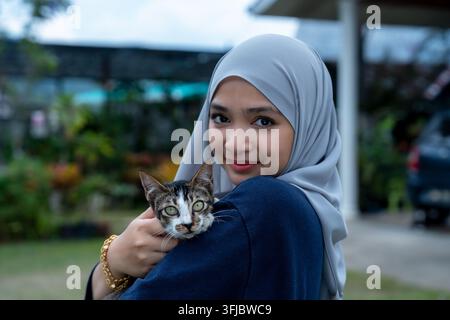 Giovane donna felice con gatto tabby Foto Stock