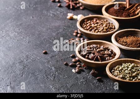 Varietà di messa a terra, il caffè istantaneo, diversi i chicchi di caffè e lo zucchero di canna, spezie in ciotole di legno scuro su sfondo di texture. Spazio di copia Foto Stock