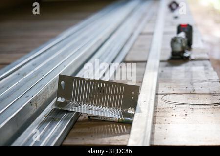 Una staffa di costruzione metallica su un banco da lavoro in legno con canali in acciaio e utensile elettrico che crea una scena di officina attiva Foto Stock
