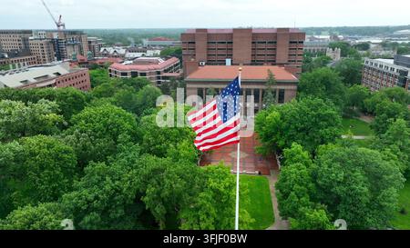 Bandiera americana che sventola su Ingalls Mall nel campus dell'Università del Michigan. Ripresa aerea con vista sugli edifici accademici e sul Burton Memorial To Foto Stock