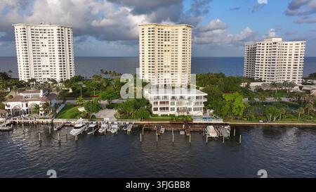 Yacht e barche su un molo privato con villa e ville sullo sfondo. Complesso di appartamenti di lusso con vista sull'oceano a Boca Raton, Florida, USA. Vista aerea la Foto Stock