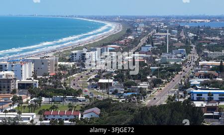 Spiaggia sabbiosa curva si estende lungo l'Oceano Atlantico a Cocoa Beach in Florida, strada costiera fiancheggiata da hotel e condomini che seguono una dolce curva Foto Stock