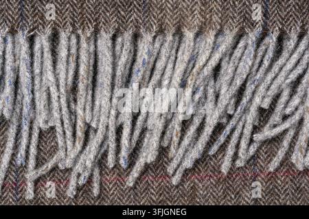Vista macro di un tessile denso e soffice grigio-marrone con fibre allungate e sottili fili blu e rossi intrecciati ovunque. Foto Stock
