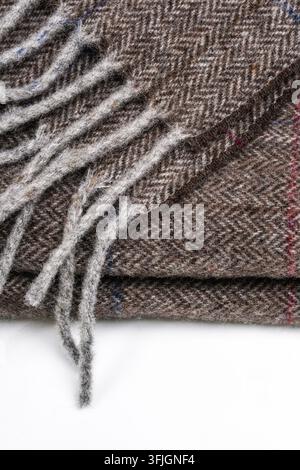 Prima dettagliata di un tessuto intessuto marrone e grigio con fibre sfocate, frange sciolte e un motivo a quadri sottile su uno sfondo chiaro Foto Stock