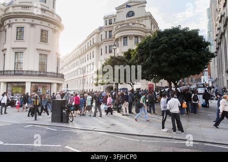 Pedoni si radunano su una strada di Londra fuori dal classico Ministero degli Affari Esteri, del Commonwealth e dello Sviluppo vicino a una cabina telefonica rossa. Foto Stock