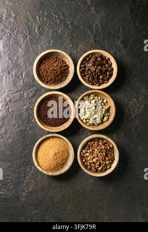 Varietà di messa a terra, il caffè istantaneo, diversi chicchi di caffè, zucchero di canna in ciotole di legno in fila più scuro dello sfondo texture. Vista superiore, spazio Foto Stock