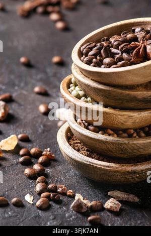 Varietà di messa a terra, il caffè istantaneo, diversi i chicchi di caffè e lo zucchero di canna, spezie in ciotole di legno scuro su sfondo di texture. Close up Foto Stock