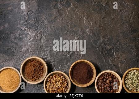 Varietà di messa a terra, il caffè istantaneo, diversi chicchi di caffè, zucchero di canna in ciotole di legno in fila più scuro dello sfondo texture. Vista superiore, spazio Foto Stock