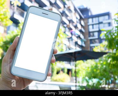 Telefono nelle mani con uno schermo isolato sullo sfondo dell'edificio hotle. Spazio per la tua pubblicità. Foto Stock