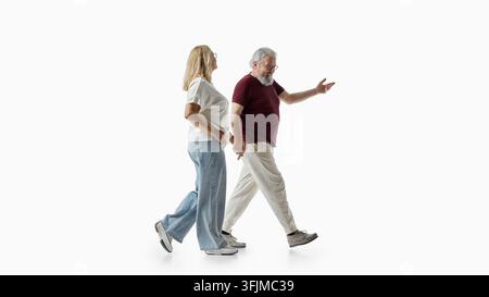 Duetto avventuroso di anziani che passeggia in uno studio bianco con interesse animato Foto Stock