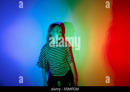 Giovane donna felice con luce arcobaleno colorata Foto Stock