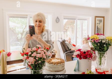 Nonna che scatta una foto della tavola della festa di compleanno Foto Stock