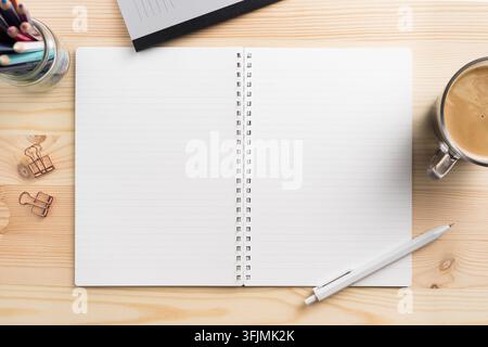 Vista dall'alto di un modello di quaderno a spirale aperto con cancelleria su scrivania di legno chiaro con spazio per copiare Foto Stock