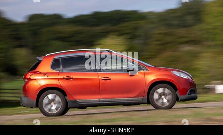 Milton Keynes; Regno Unito - 20 settembre 2026: auto Peugeot 2008 rossa del 2015 in corsa su una strada britannica Foto Stock