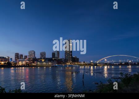 Silhouette moderna illuminata della città e ponte ad arco sul fiume Danubio al crepuscolo a Bratislava. Foto Stock