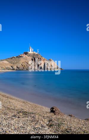 Il faro di Cabo de Gata si erge maestoso sopra una spiaggia serena, catturato con esposizione lunga diurna. Parte del Parco Naturale di Cabo de Gata-Níjar, Almeri Foto Stock