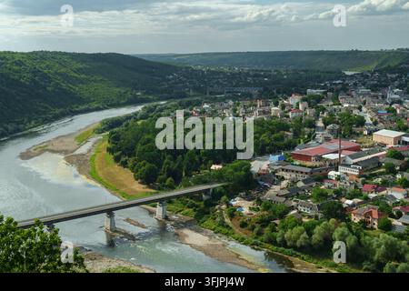 Bella vista panoramica ad alta angolazione della città di Zalishchyky annidata nel pittoresco canyon del fiume Dniester, Ucraina. L'inquadratura cattura un ponte ferroviario Foto Stock