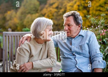 Un momento tranquillo per una coppia senior, godendosi una calda serata autunnale in terrazza. Foto Stock