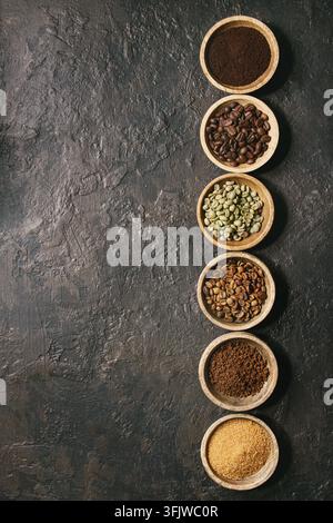 Varietà di messa a terra, il caffè istantaneo, diversi chicchi di caffè, zucchero di canna in ciotole di legno in fila più scuro dello sfondo texture. Vista superiore, spazio Foto Stock