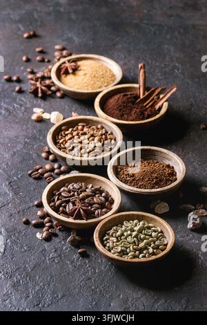 Varietà di messa a terra, il caffè istantaneo, diversi i chicchi di caffè e lo zucchero di canna, spezie in ciotole di legno scuro su sfondo di texture. Spazio di copia Foto Stock