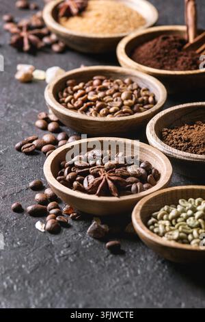 Varietà di messa a terra, il caffè istantaneo, diversi i chicchi di caffè e lo zucchero di canna, spezie in ciotole di legno scuro su sfondo di texture. Close up Foto Stock