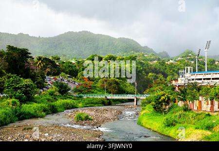 Vista panoramica del fiume Roseau che scorre attraverso colline verdi e lussureggianti verso lo stadio Windsor Park a Roseau, Dominica Foto Stock