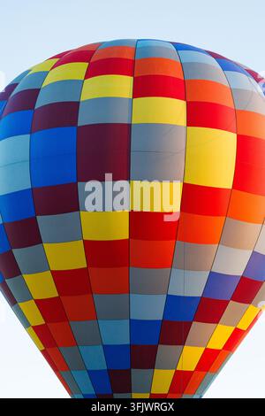 Involucro di mongolfiera a motivi colorati contro un cielo blu Foto Stock