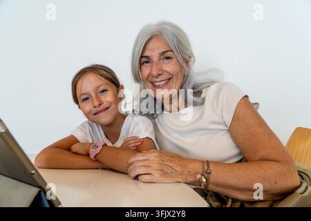 Nonna e nipote che si legano, sorridendo, usando un tablet digitale Foto Stock
