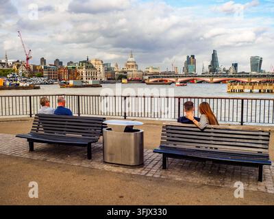 Due coppie sedute su una panchina al Southbank del fiume Tamigi - Londra, Inghilterra Foto Stock