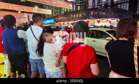 BANGKOK, THAILANDIA - 29 GENNAIO 2025: Persone radunate lungo la strada di notte nel quartiere cinese di Bangkok per assistere a una sfilata del Capodanno cinese. Foto Stock