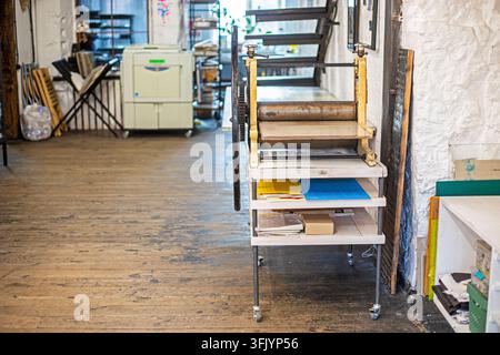 Un interno semplice con una pressa per incisioni e scaffali per opere d'arte grafiche Foto Stock