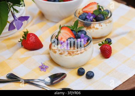 Prima vista di un dessert ai frutti di bosco con fiori commestibili e fragole fresche sul tavolo Foto Stock