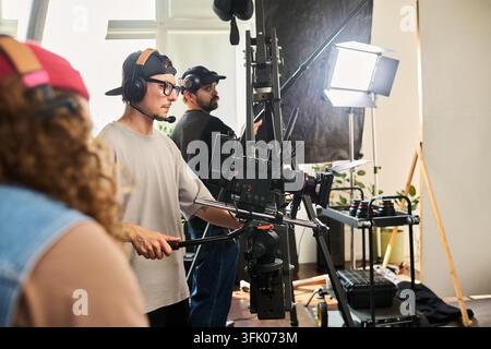 Cameraman che opera una videocamera professionale sul set di studio Foto Stock