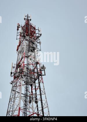Torre di telecomunicazione con più antenne contro un cielo sereno, che illustra la comunicazione senza fili e l'infrastruttura della rete mobile. Foto Stock