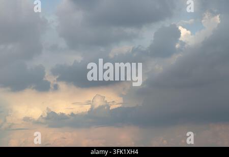 Uno studio atmosferico magnifico che cattura la morbida transizione del crepuscolo mentre una luce solare gentile illumina il cielo inferiore. Cumuli nuvolosi pesanti, grigio ardesia Foto Stock