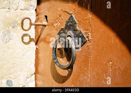 Primo piano di un batacchio in ferro antico montato su una porta di legno stagionata di un monastero a Creta, Grecia Foto Stock