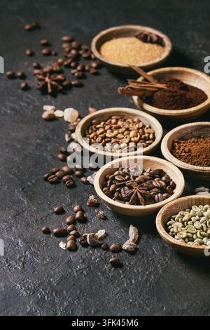 Varietà di messa a terra, il caffè istantaneo, diversi i chicchi di caffè e lo zucchero di canna, spezie in ciotole di legno scuro su sfondo di texture. Spazio di copia Foto Stock