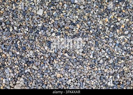 Piccoli ciottoli grigi e beige, sfondo texture. Vista dall'alto di piccoli ciottoli grigi, beige e blu che formano una texture naturale densa e ruvida. Foto Stock