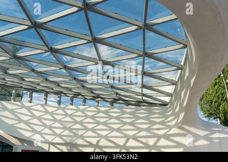 Una vista a bassa angolazione di una moderna struttura a tetto in vetro con una cornice metallica geometrica di motivi triangolari e a rombo. Il sole splende attraverso il vetro, c Foto Stock