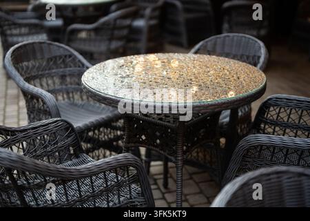 Terrazza all'aperto del caffè vuota con tavoli e sedie bagnati dopo la pioggia autunnale durante il periodo di bassa stagione Foto Stock
