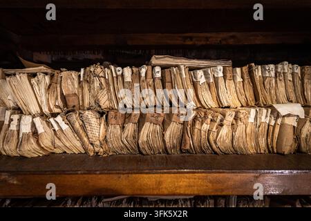 File antiche, dossier e pile di libri vintage ordinatamente disposti su una libreria Foto Stock
