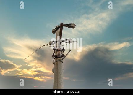 Vista ad angolo basso della cima di un vecchio palo dell'energia elettrica in una giornata nuvolosa Foto Stock