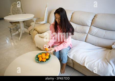 Bella donna che mangia mandarini a casa Foto Stock