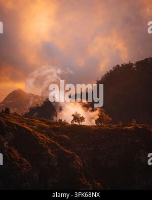 Vista del paesaggio montuoso con nebbia che si sposta sul crinale durante un tramonto dorato a Madeira, Portogallo Foto Stock